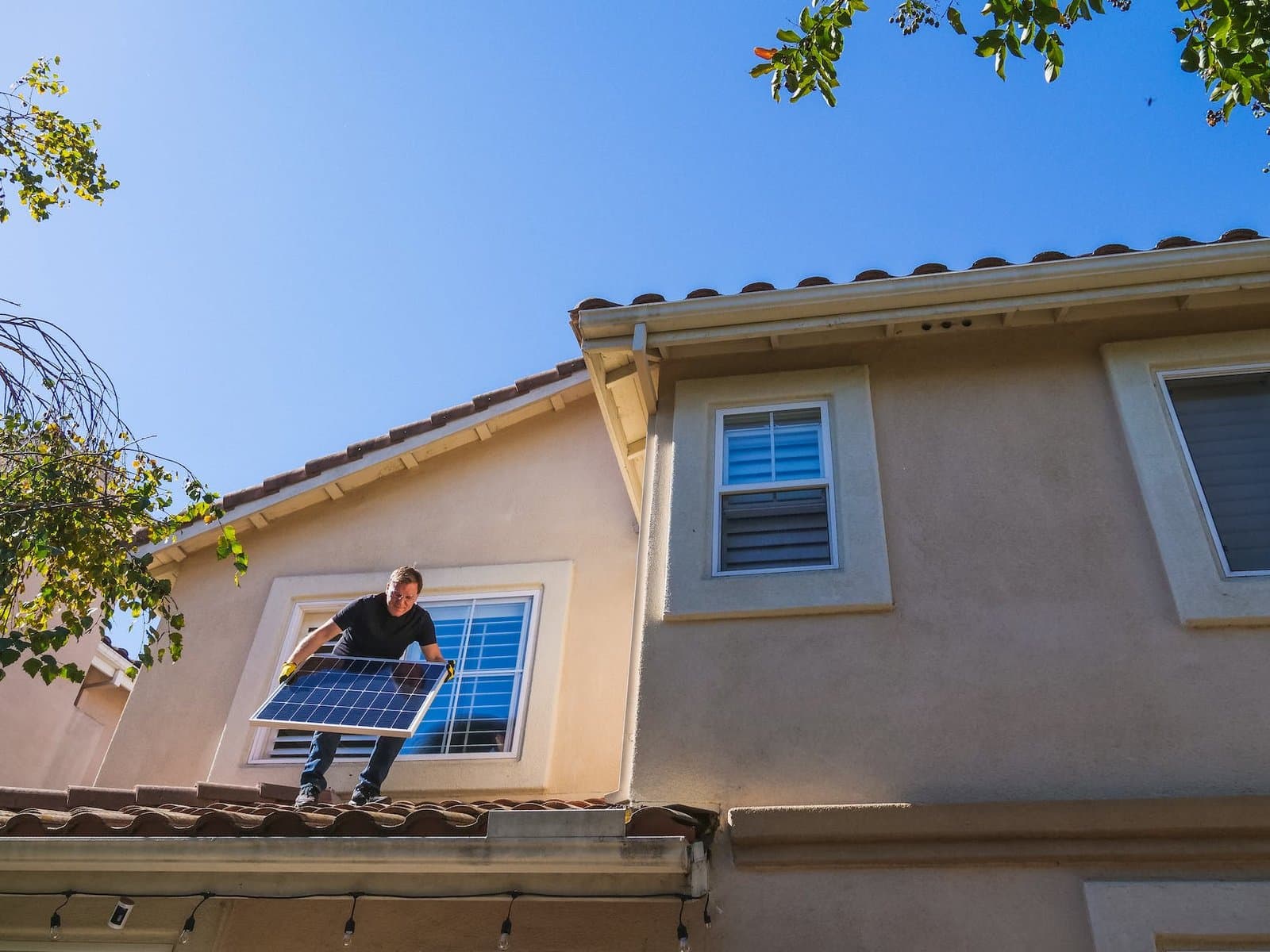 a man standing on the roof while holding a solar panel What is a Green Mortgage?