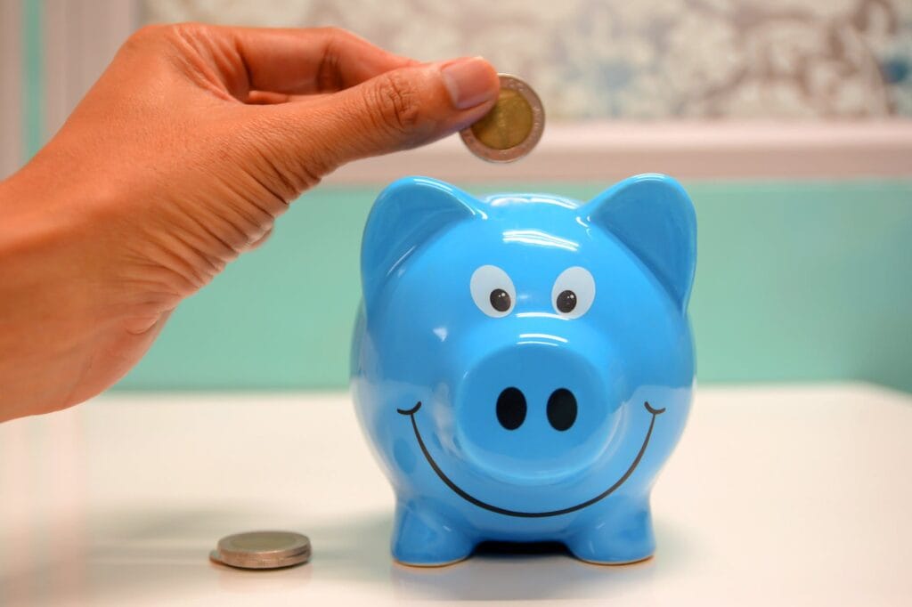 person putting coin in a piggy bank How Much Does It Cost to Sell a House