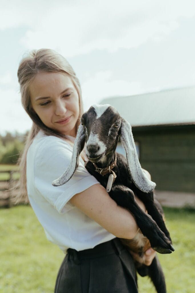 woman in white shirt hugging goat homesteading in Tampa