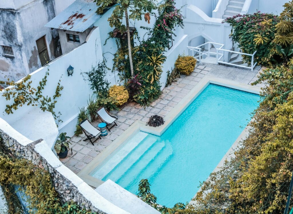 Relaxing outdoor villa view with a turquoise pool surrounded by lush greenery.
